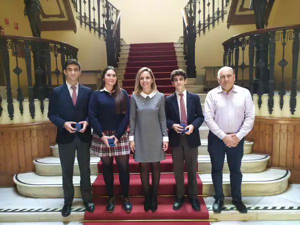 Maribel Sánchez recibe a Ios tres alumnos del centro educativo que han participado en el primer Torneo de Debate Económico en Bachillerato.