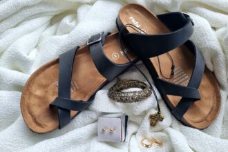 a pair of sandals, a ring, and a bracelet on a white blanket